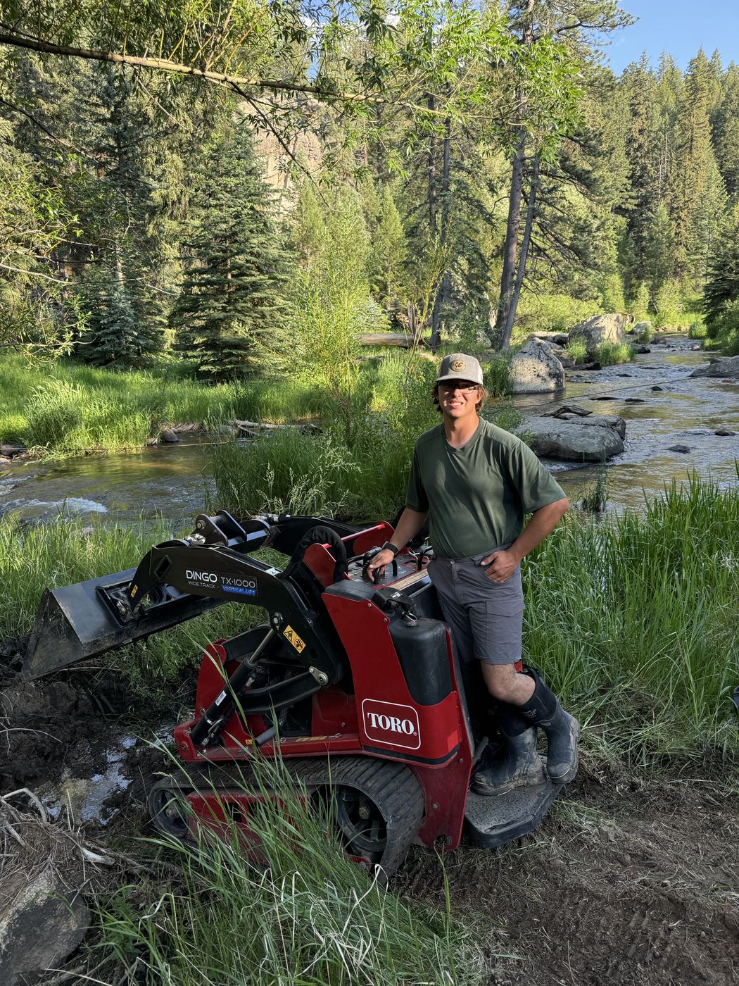 Josh, founder and owner of Lawn Smiles, on his Toro compact track loader beside a creek