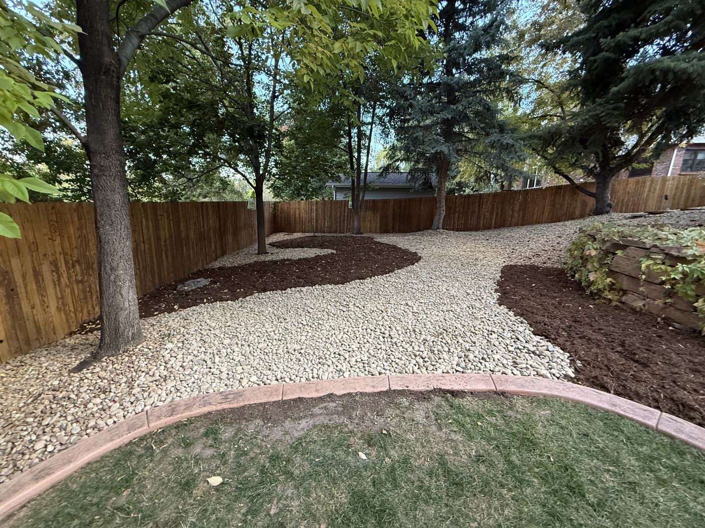 Xeriscaped backyard with rock, mulch and curved edging